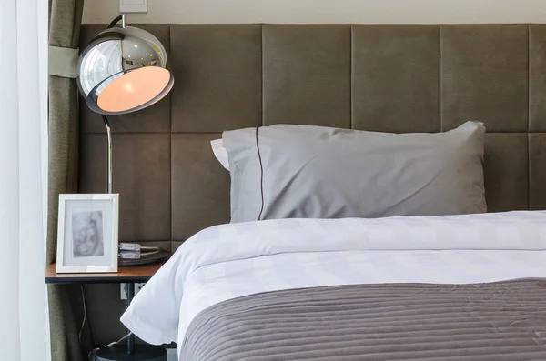 Grey pillow on bed with lamp — Stock Photo, Image