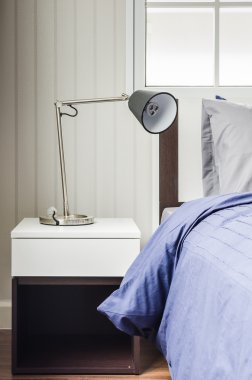 Yatak odasında beyaz komodinin üzerinde modern lamba