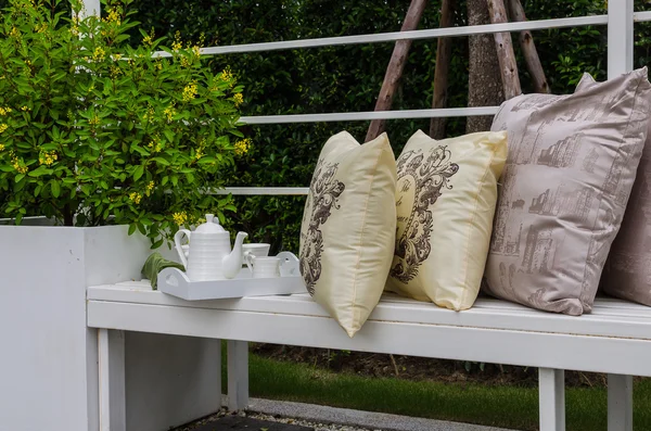 Çay seti ve yastık beyaz bankta — Stok fotoğraf