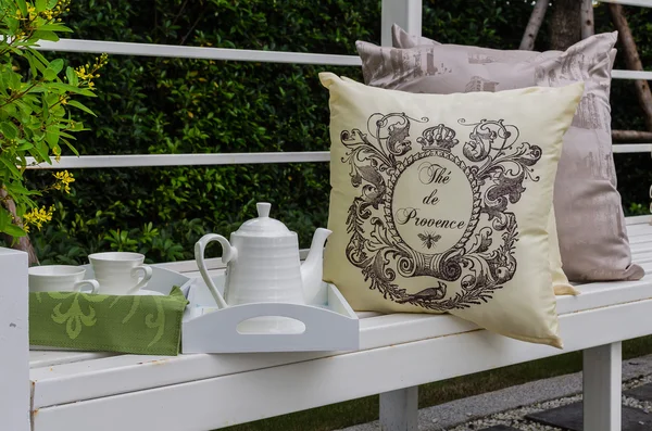 Tray of white tea set with pillows on bench — Stock Photo, Image