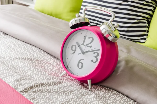 Pink alarm clock on bed — Stock Photo, Image