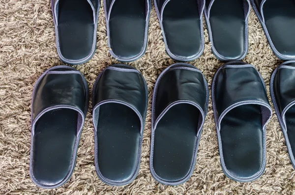 Fila di pantofole nere su tappeto — Foto Stock