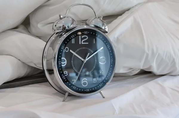Classical alarm clock on bed — Stock Photo, Image