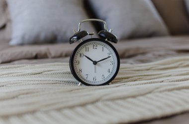 gri yastık ile kahverengi yatakta siyah çalar saat 