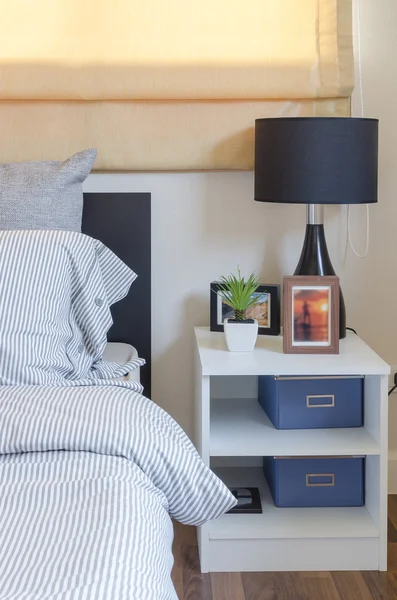 Белый стол с растением в вазе и черная лампа в спальне — стоковое фото
