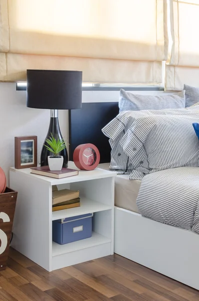Mesa blanca con planta en jarrón sobre libro y lámpara negra en dormitorio —  Fotos de Stock