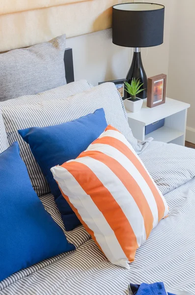 Orange und blaue Kissen auf dem Bett — Stockfoto