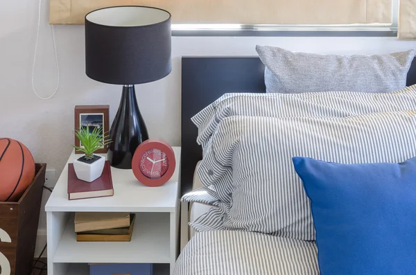 Blaues Kissen auf modernem Bett mit schwarzer Lampe auf weißem Tisch — Stockfoto