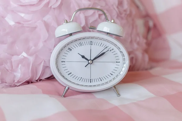 White modern alarm clock on pink bed — Stock Photo, Image