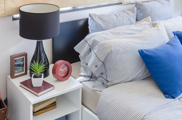 Blauwe kussen op moderne bed met zwarte lamp op witte tafel — Stockfoto