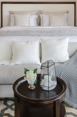 Yatak odasında ahşap yuvarlak masa üzerinde cam vazoda bitkiler