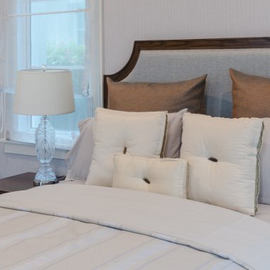 Yatak odasında lüks lambası ile beyaz yatakta beyaz yastıklar