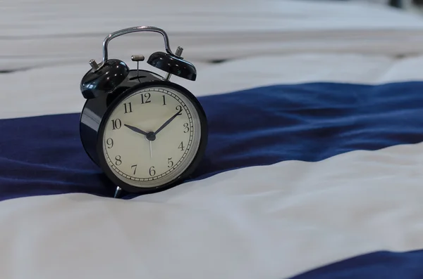 Black classic alarm clock on bed — Stock Photo, Image