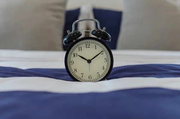 Relógio de alarme clássico preto na cama — Fotografia de Stock