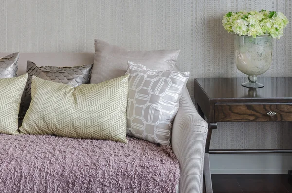 Luxusní pohovka s polštáři a vázy, rostlin na dřevěný stůl — Stock fotografie