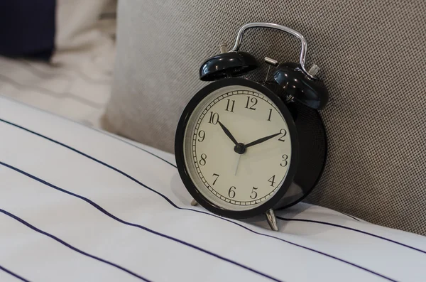 Black classic alarm clock on bed — Stock Photo, Image