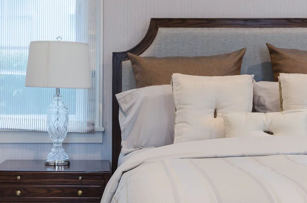 Белые подушки на белой кровати с роскошной лампой в спальне — стоковое фото