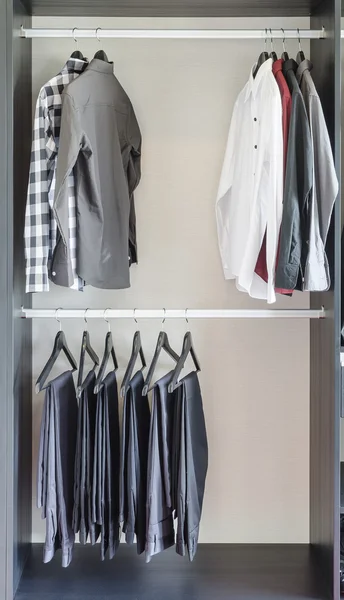Ряд брюк и рубашек в шкафу — стоковое фото