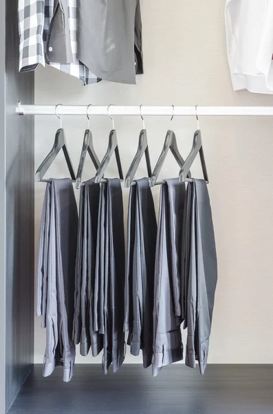 Ряд черных брюк висит в шкафу — стоковое фото