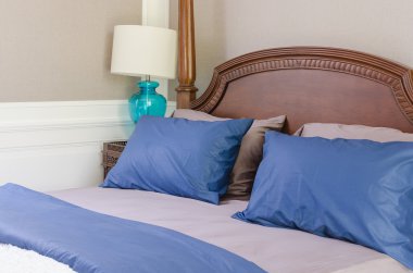 mavi ve gri yastık modern lamba ile klasik ahşap yatak