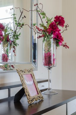 ahşap masa üzerinde cam vazoda kırmızı çiçek