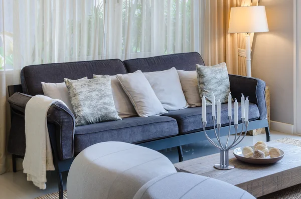 Kussens op blauwe sofa met lamp en kaarsenhouders op houten tafel — Stockfoto