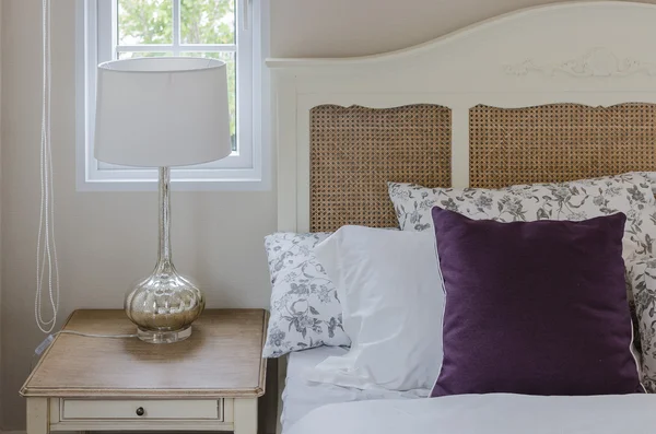 Almohada púrpura en cama de madera con lámpara en el dormitorio — Foto de Stock
