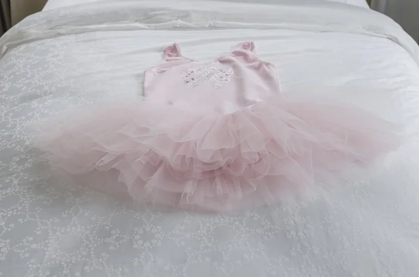 Różowa sukienka dziewczyny na łóżku — Zdjęcie stockowe