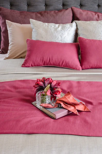 Ліжко червоного кольору та подушки з рослиною у скляній вазі на підносі — стокове фото