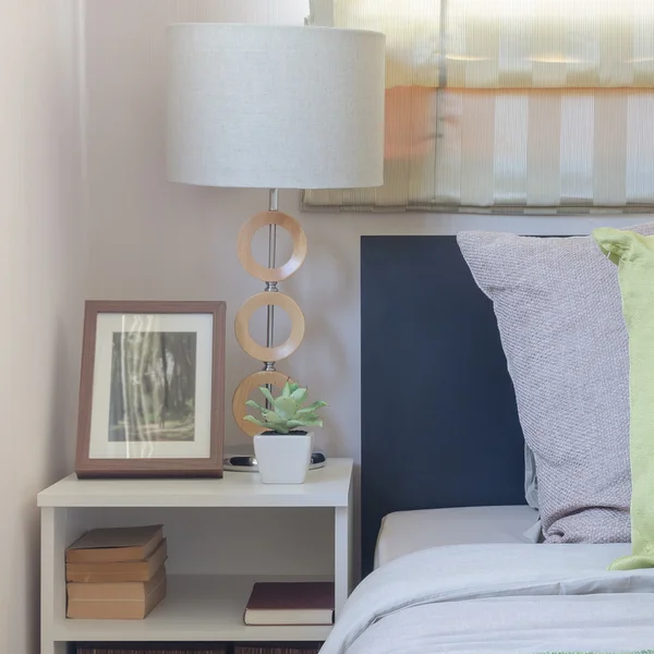 Современная белая лампа на столе с подушками на кровати — стоковое фото