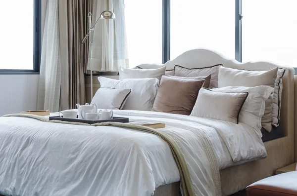 Teetasse auf klassischem Bett mit Kissen lizenzfreie Stockbilder
