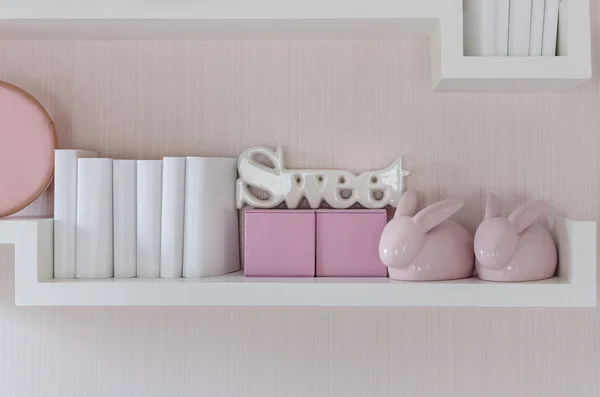 Dekorativa hylla på rosa vägg med kaniner keramik och ordet "swe — Stockfoto
