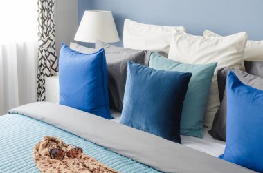blue pillow on bed with glasses on cloth in modern bedroom