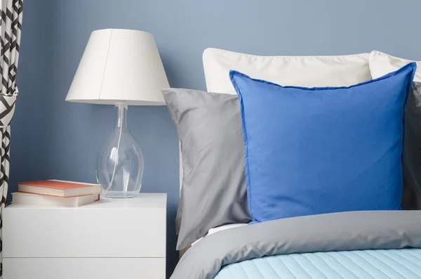 Blue pillow on bed with glass lamp on white table in modern blue — Stock Photo, Image