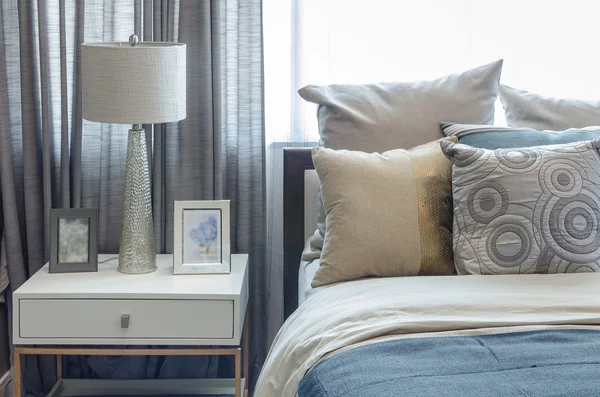 Подушки на синем диване с лампой — стоковое фото