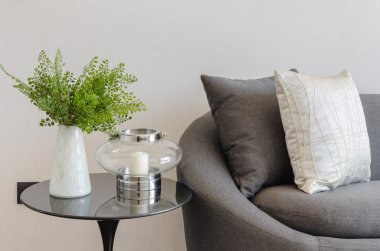 plant in white vase on round table with sofa and pillows
