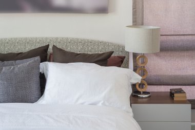 Beyaz yastık masada beyaz lamba ile modern yatak odası