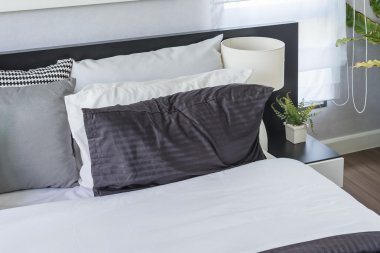 Beyaz yastık masada beyaz lamba ile modern yatak odası 