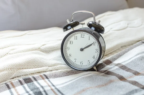 Moderner schwarzer Wecker auf dem Bett im Schlafzimmer — Stockfoto