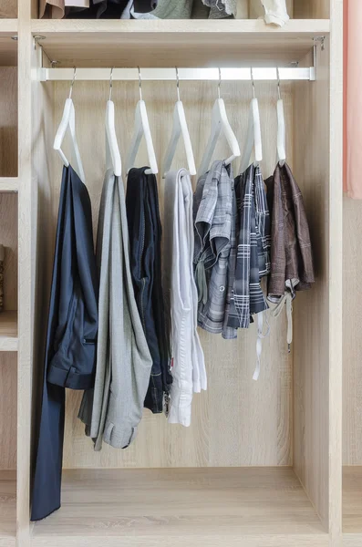 Clothes hanging in wooden wardrobe — Stock Photo, Image