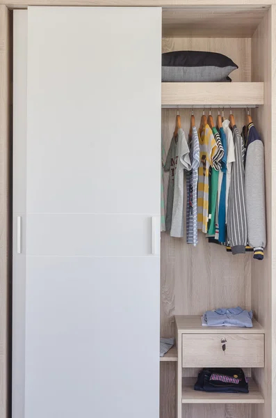 Детская одежда висит в белом шкафу — стоковое фото