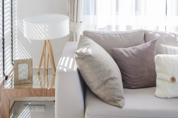 Гостиная в современном стиле с подушками на диване и современной лампой на — стоковое фото