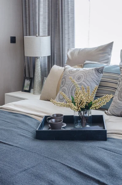 Tray of cup and glass vase of plant on bed — Stock Photo, Image