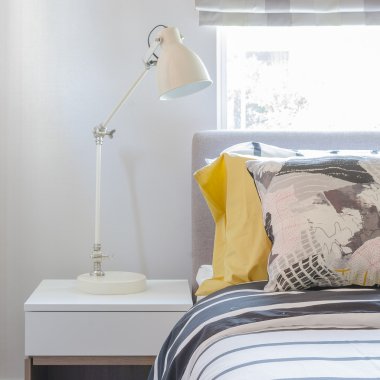 Beyaz ahşap masa tarafında beyaz lamba ile modern yatak odası