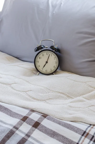 Modern black alarm clock on bed — Stock Photo, Image