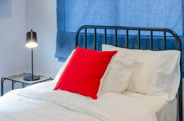 Tabl に黒ランプと青いカーテン白いベッドの上に赤い枕 — ストック写真