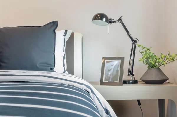 Black and white pillows and blanket on bed with black lamp on ta — Stock Photo, Image