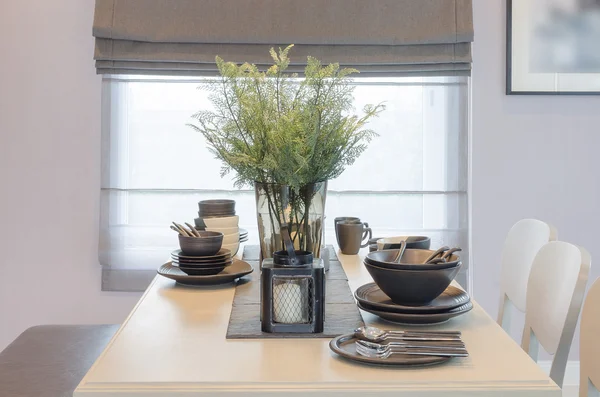 Hölzerner Esstisch mit Glasvase mit Pflanze — Stockfoto
