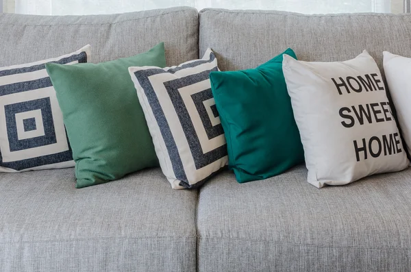 Fila de almohadas verdes y blancas en sofá gris — Foto de Stock