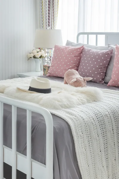 Almohadas de color rosa con muñeca rosa en la cama de madera blanca y sombrero clásico — Foto de Stock